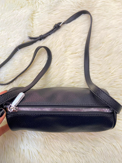 Cartera, negra pequeña con lazo ajustable, en forma de cilindro.