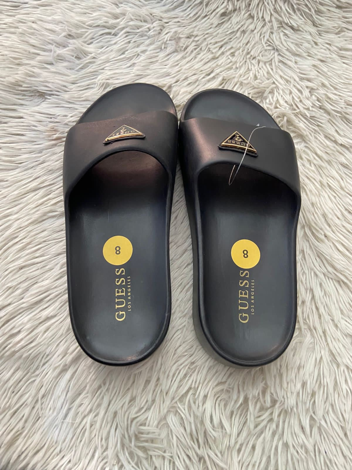 Sandalias GUESS original, negra con plataformas y placa GUESS en frente en color dorado y negro.