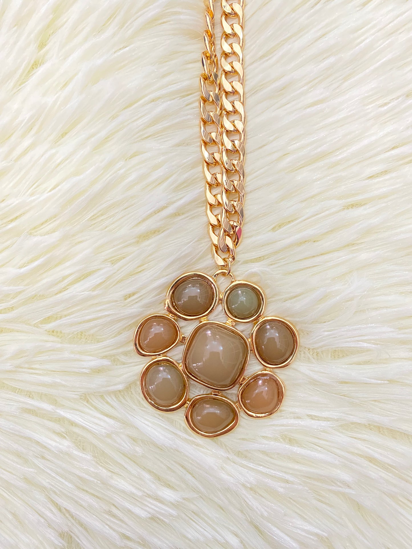 Cadena, dorada con dije en forma de flor y piedras verde.