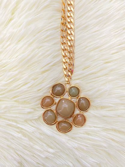 Cadena, dorada con dije en forma de flor y piedras verde.