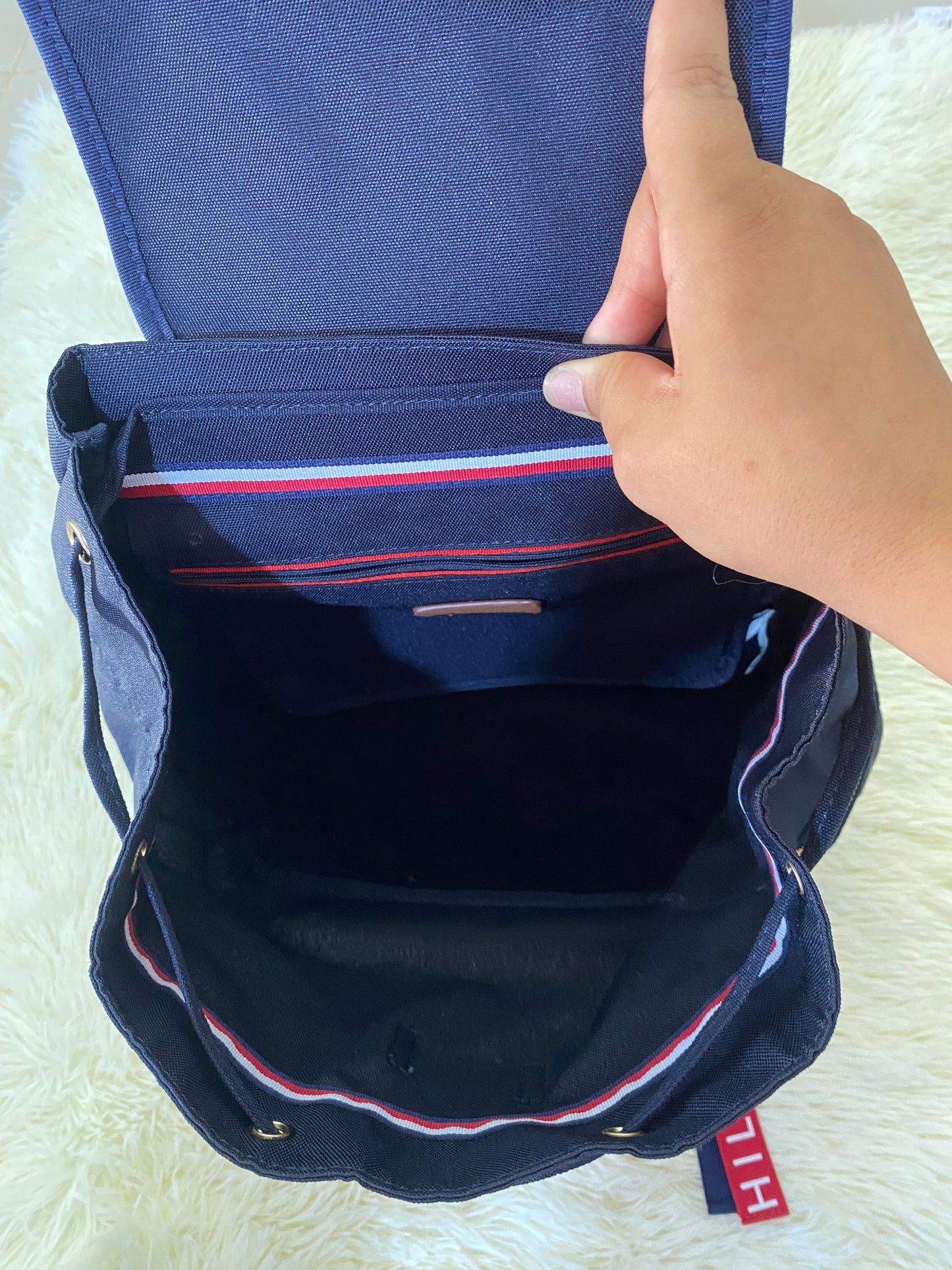 Mochila Tommy Hilfiger original en color azul marino, nombre TOMMY en grande en un bolsillo con el fondo rojo, varios compartimentos, súper espacioso.