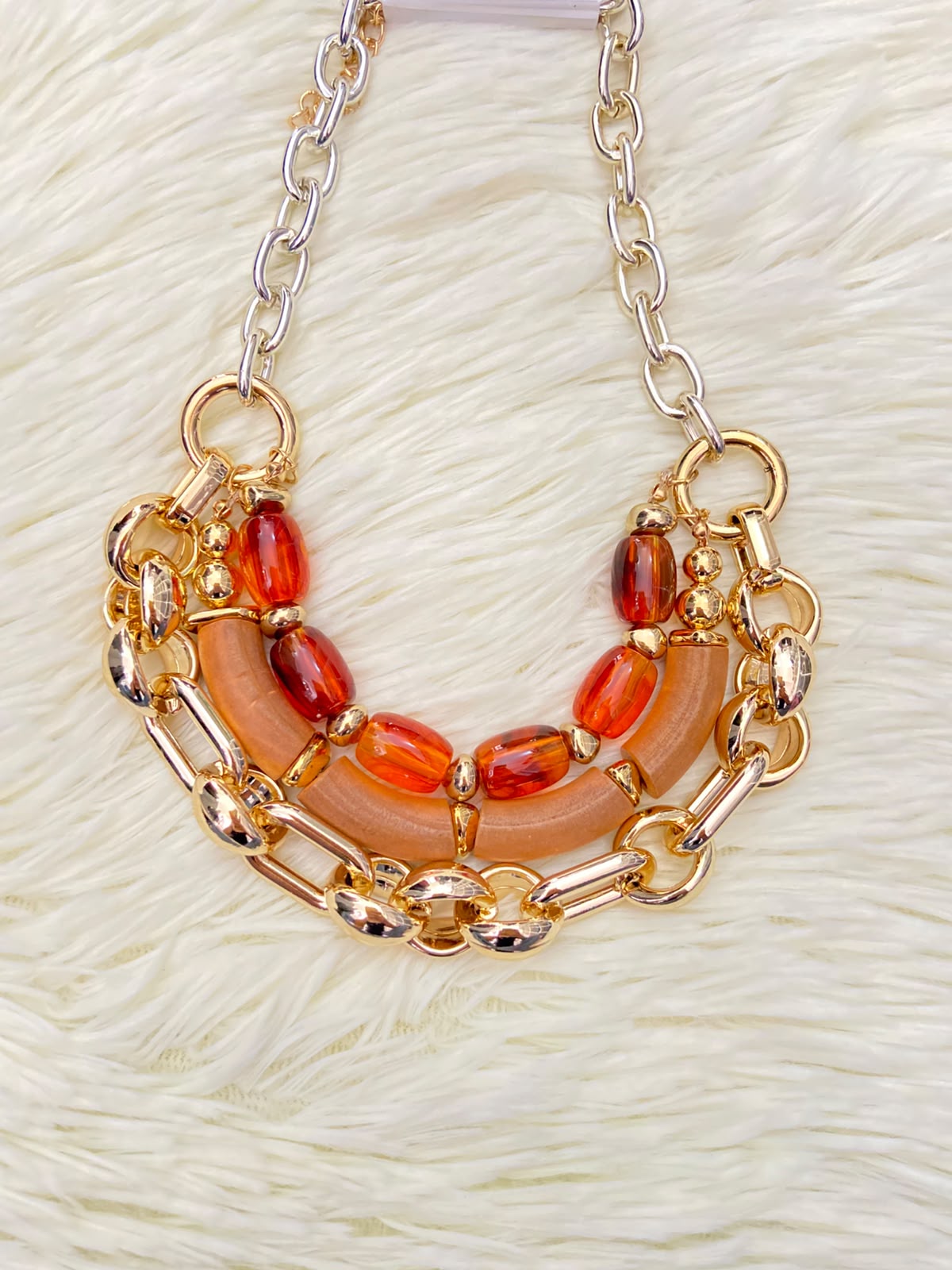Cadena, dorada con piedras en color rojo y naranja.