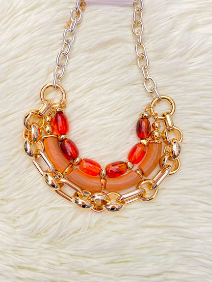 Cadena, dorada con piedras en color rojo y naranja.