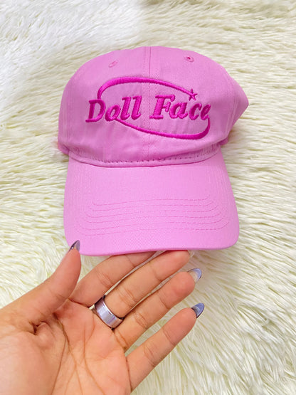 Gorra, rosada con letras DOLL FACE ( cara de muñeca).