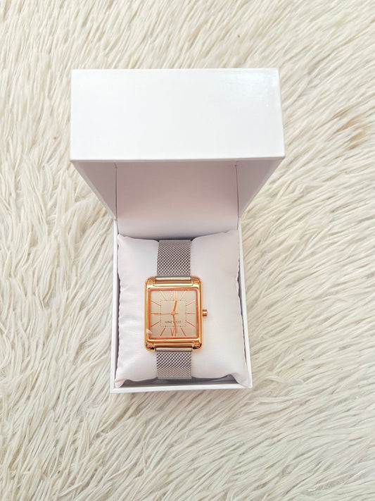Reloj Nine West Original con correa metalica en color plateado caja cuadrada en tono rose golden (oro rosado) letra de la marca Nine West en el interior.