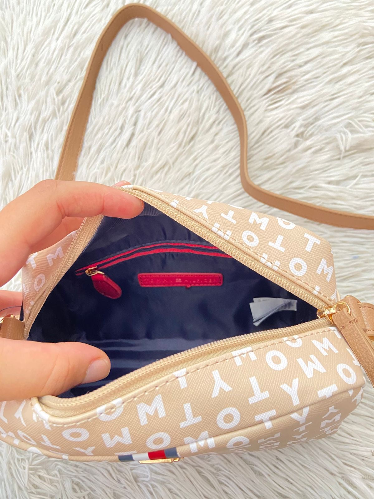 Cartera TOMMY HILFIGER original crema con estampado de letras TOMMY y banda de color rojo, azul y blanco y placa TH en dorado.