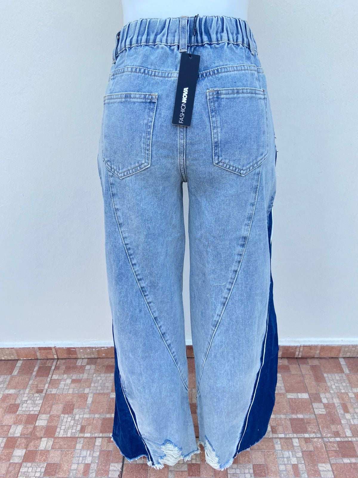 Pantalon jean azul claro con degradado blanco, tela azul oscura con blanco abajo, rotos y con pretina ajustable, ancho.