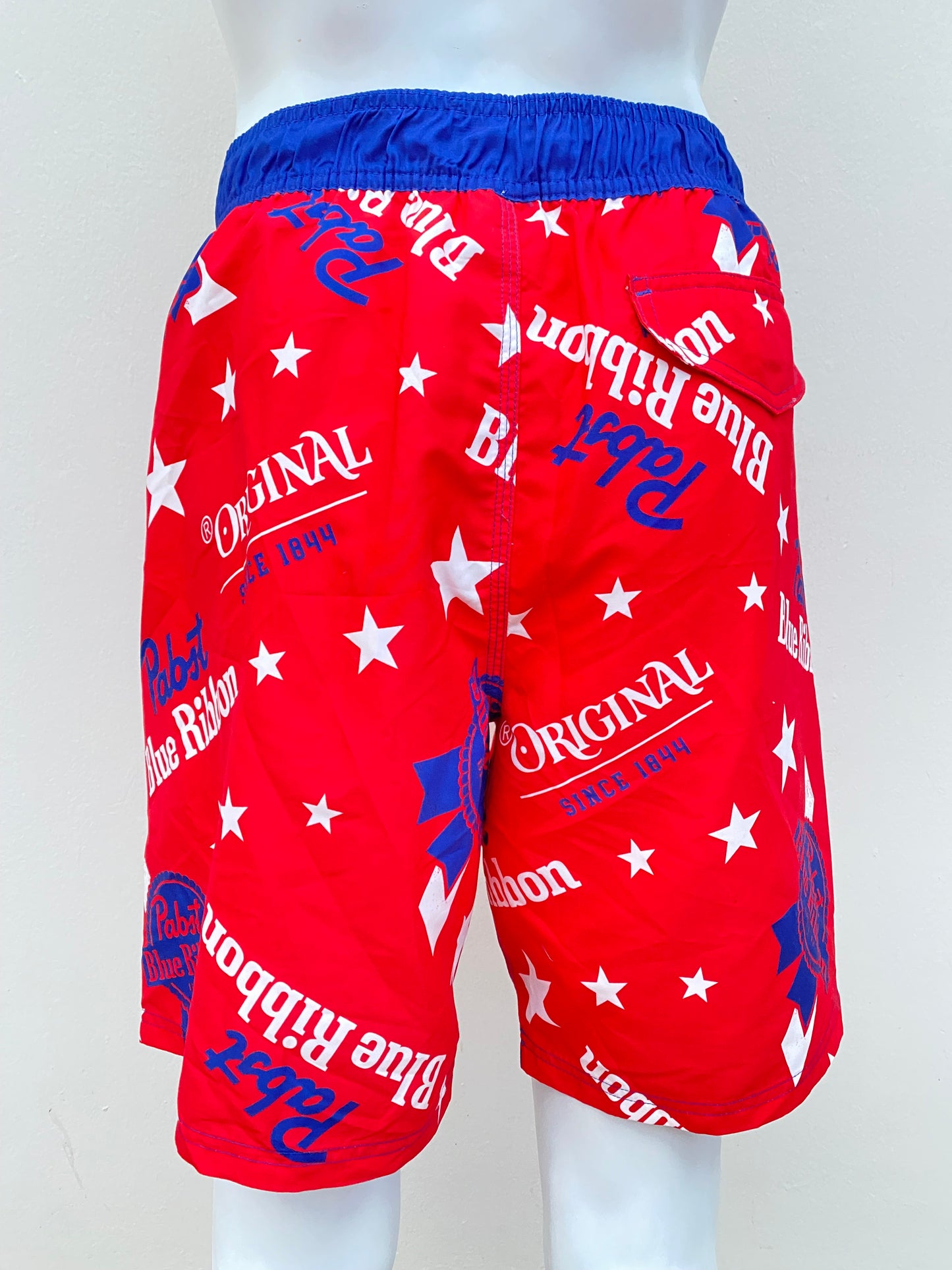 Bañador Baggy Nova Men original, roja con azul con diseños de estrellas en blanco y letras Pabst Blue Ribbon en azul.