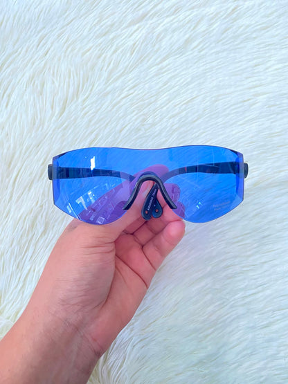 Lentes, sin montura con micas en color azul y patillas negras.