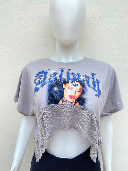 Crop-top gris con encaje abajo y estampado de la palabra Aaliyah en color azul y imagen.