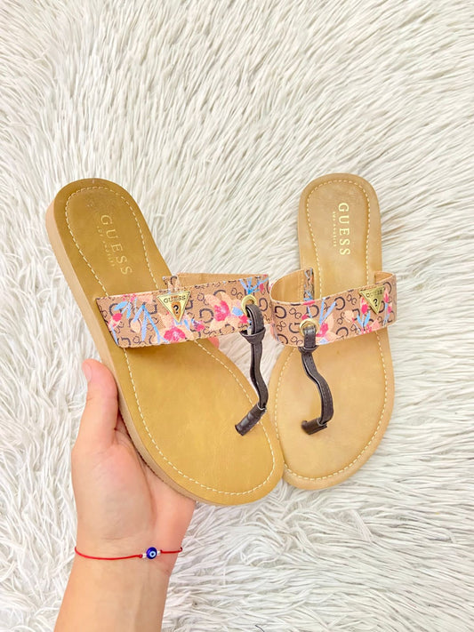 Sandalias GUESS Original, en color crema en en interior y estampado de la marca con flores y placa con la marca al frente.