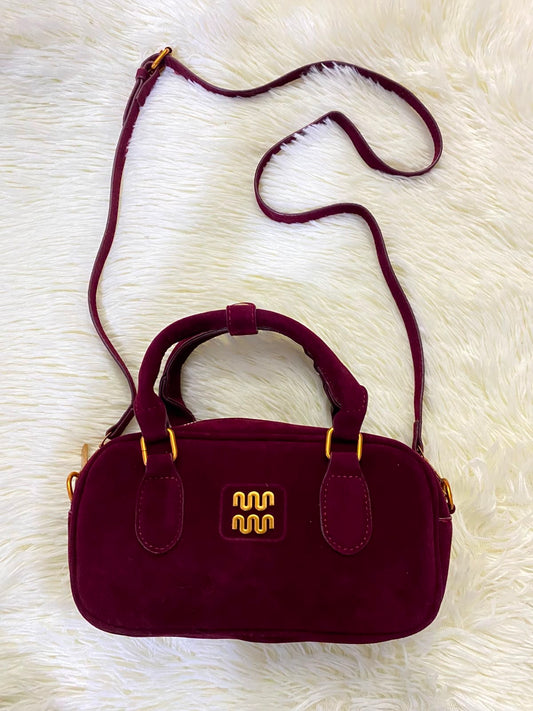 Cartera rojo vino con detalles en color dorado en terciopelo, con correa adicional.