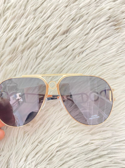 Lentes con protección UV 100-400 para proteger tu visión. Con montura en dorado y detalles en los lados.