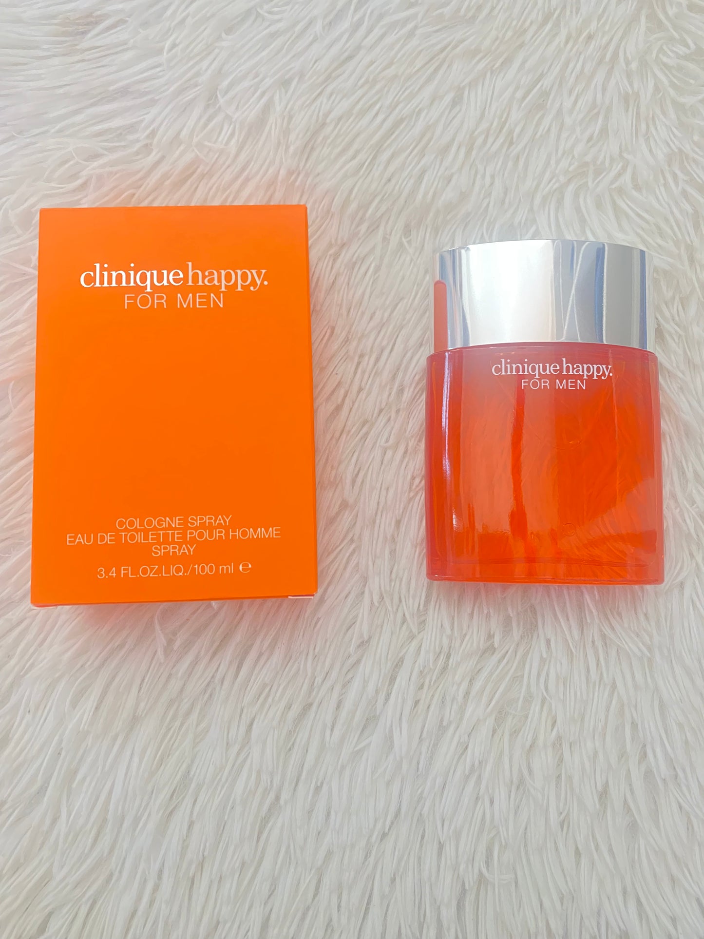 Perfume Clinique happy original, tapa plateada y frasco naranja.