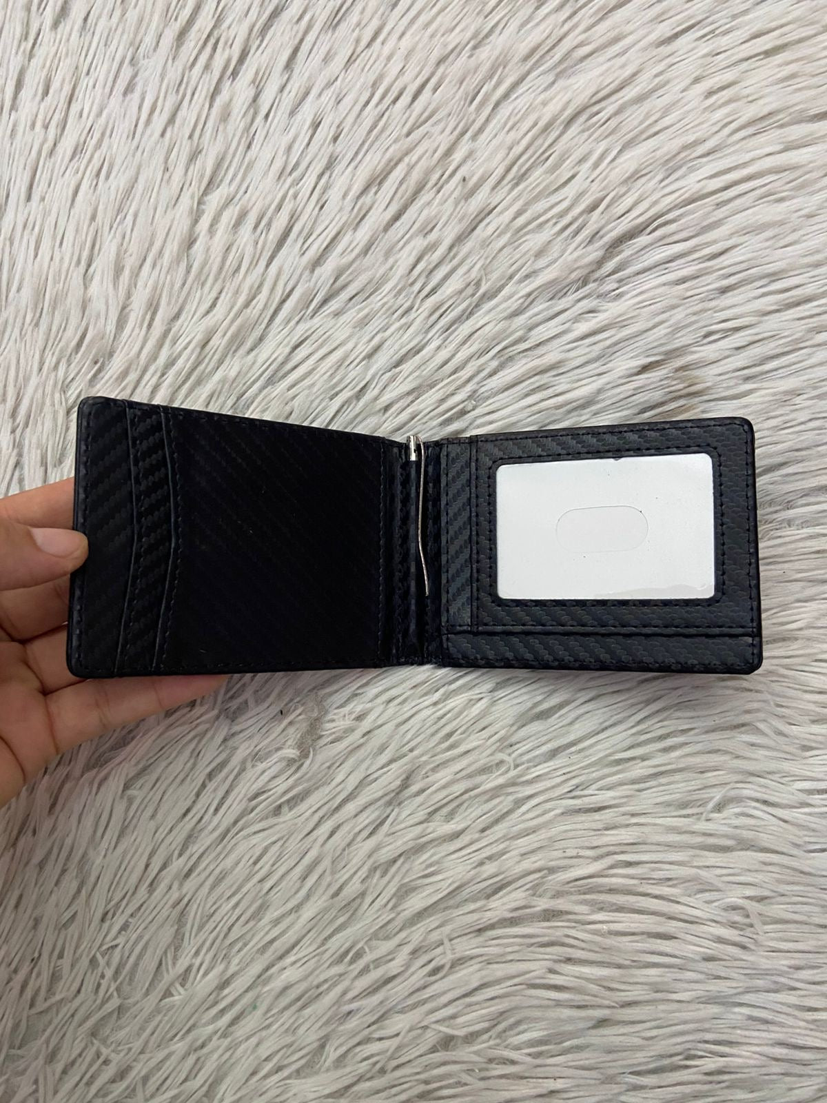 Billetera pequeña en color negra con clip para billetes, espacios para tarjetas y espacio transparente para cedula o licencia.