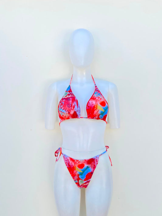 Biquini, de tres piezas con color rojo y coral combinados con detalles azules, verdes, amarillos, blancos y rosados.