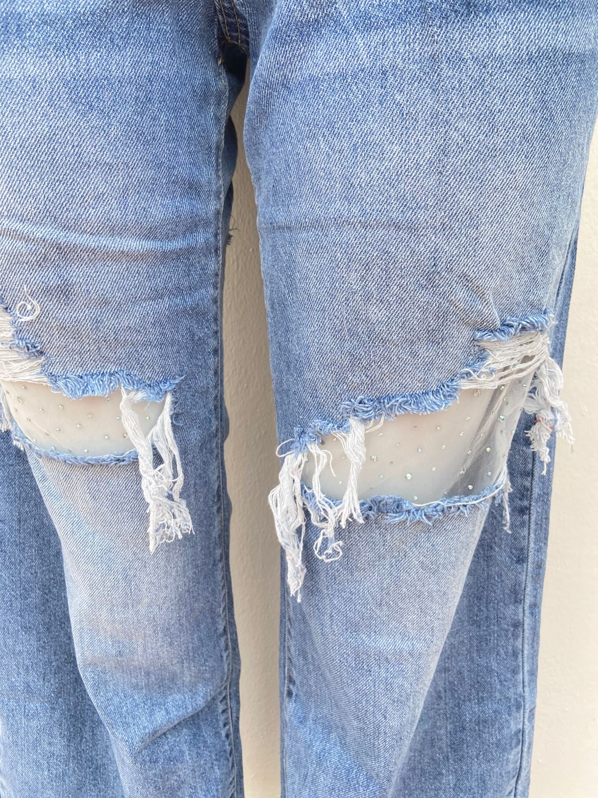 Pantalón Jean, azul con varios rasgados y malla transparente con brillos en los rotos.