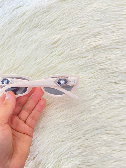 Lentes color blanco/hueso con micas oscuras con detalle plateado con negro atrás.