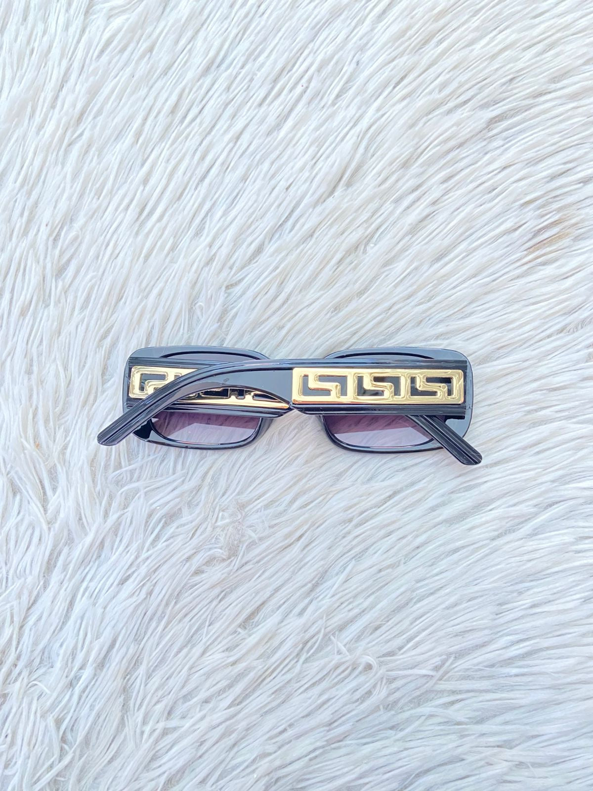 Lentes, negro con micas claras y montura en color negro y detalles en color dorado.