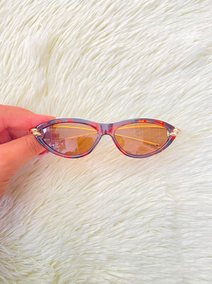 Lentes, montura con estampado de animal print, micas marrones y patillas doradas.