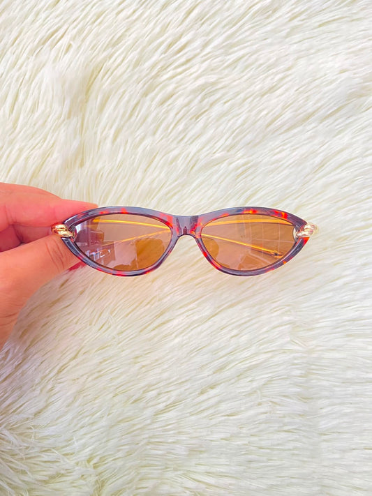 Lentes, montura con estampado de animal print, micas marrones y patillas doradas.