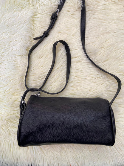 Cartera, negra pequeña con lazo ajustable, en forma de cilindro.