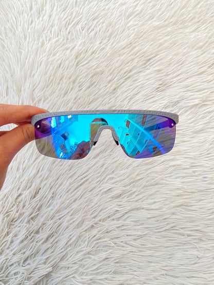Lentes, diseñados con protección UV 100-400 para proteger tu visión. Azul con montura en gris y micas que cambian de color.