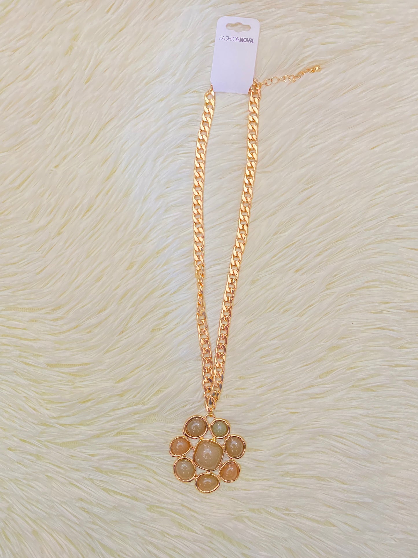 Cadena, dorada con dije en forma de flor y piedras verde.