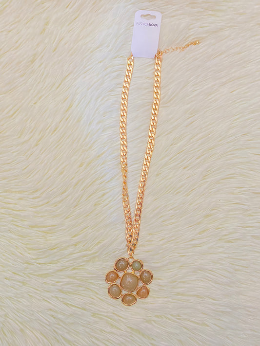 Cadena, dorada con dije en forma de flor y piedras verde.