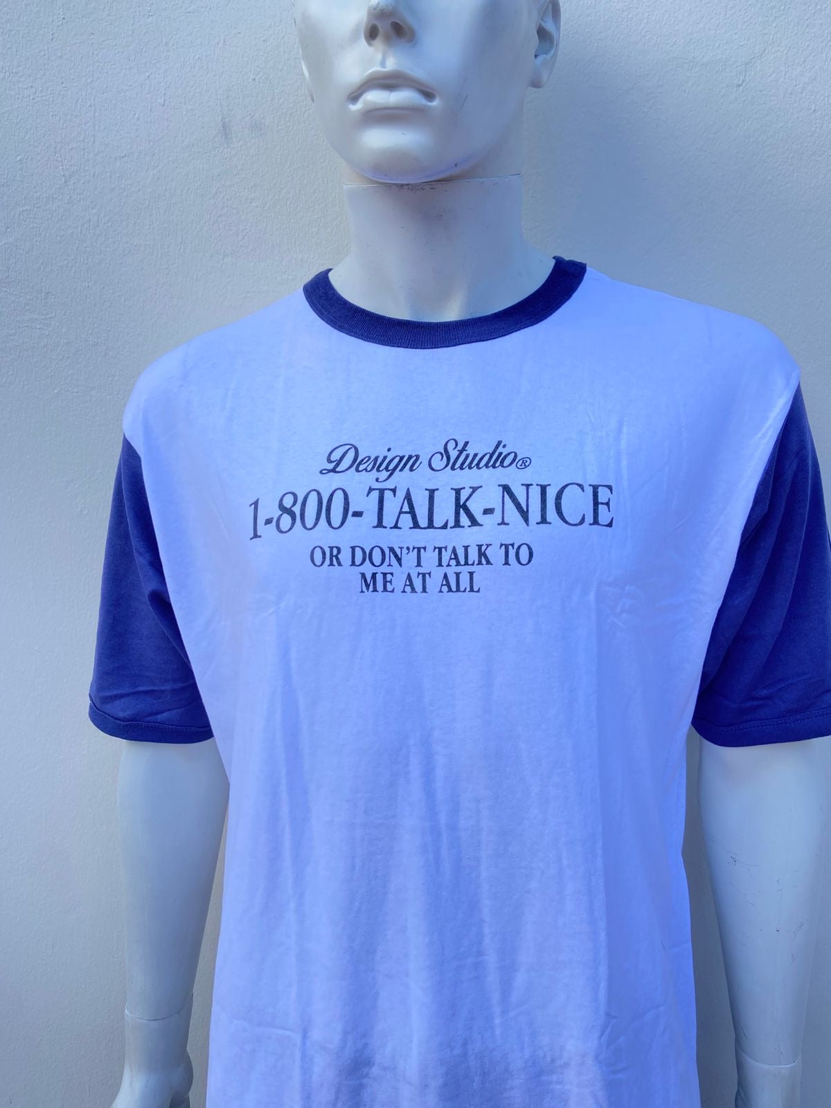 T-shirt blanco con mangas y cuello azul marino y letras negras al frente DESIGN STUDIO 1-800-Talk-Nice