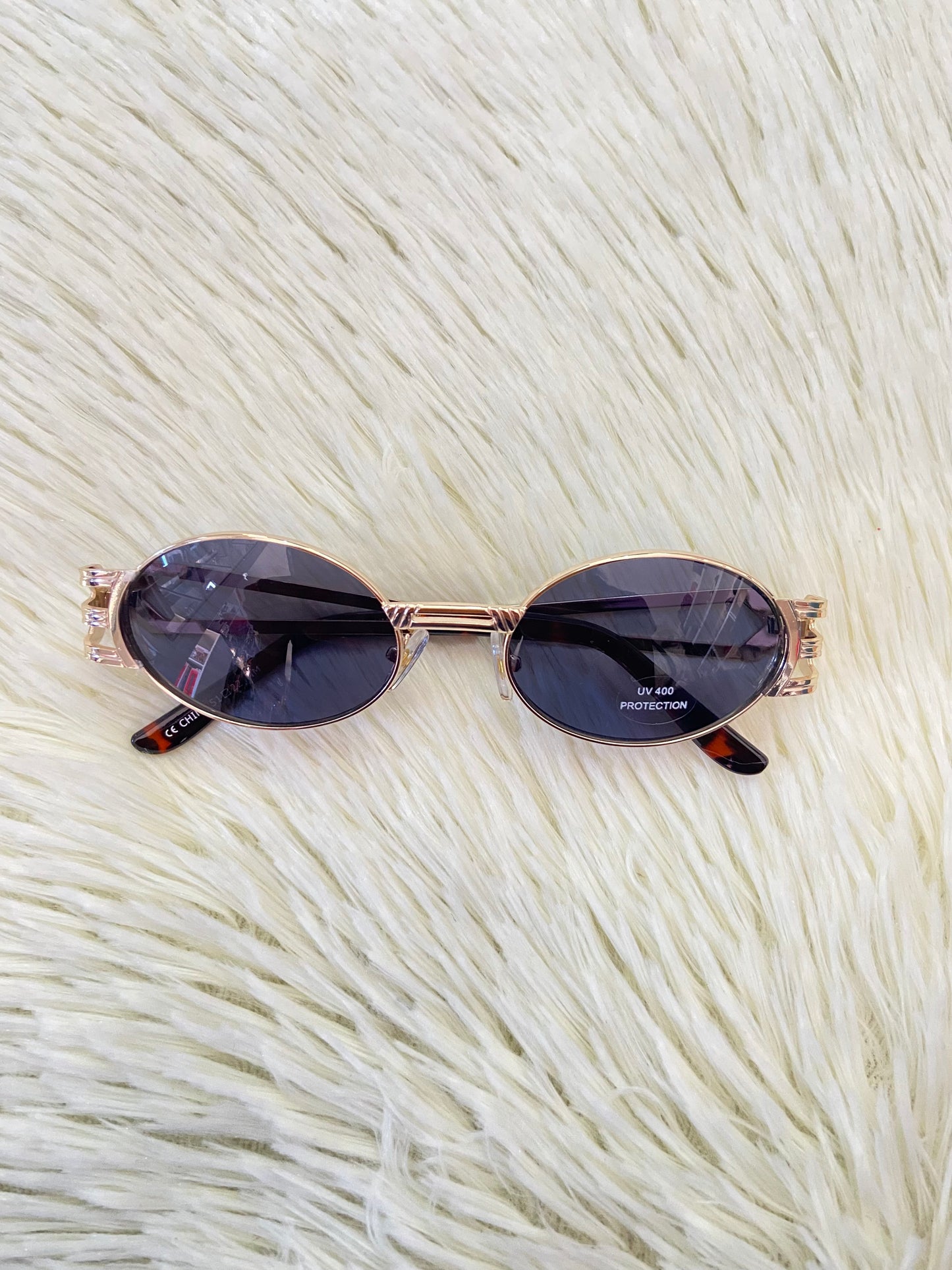 Lentes, negros con montura dorada, estilo ovalo, con protección UV 100-400.