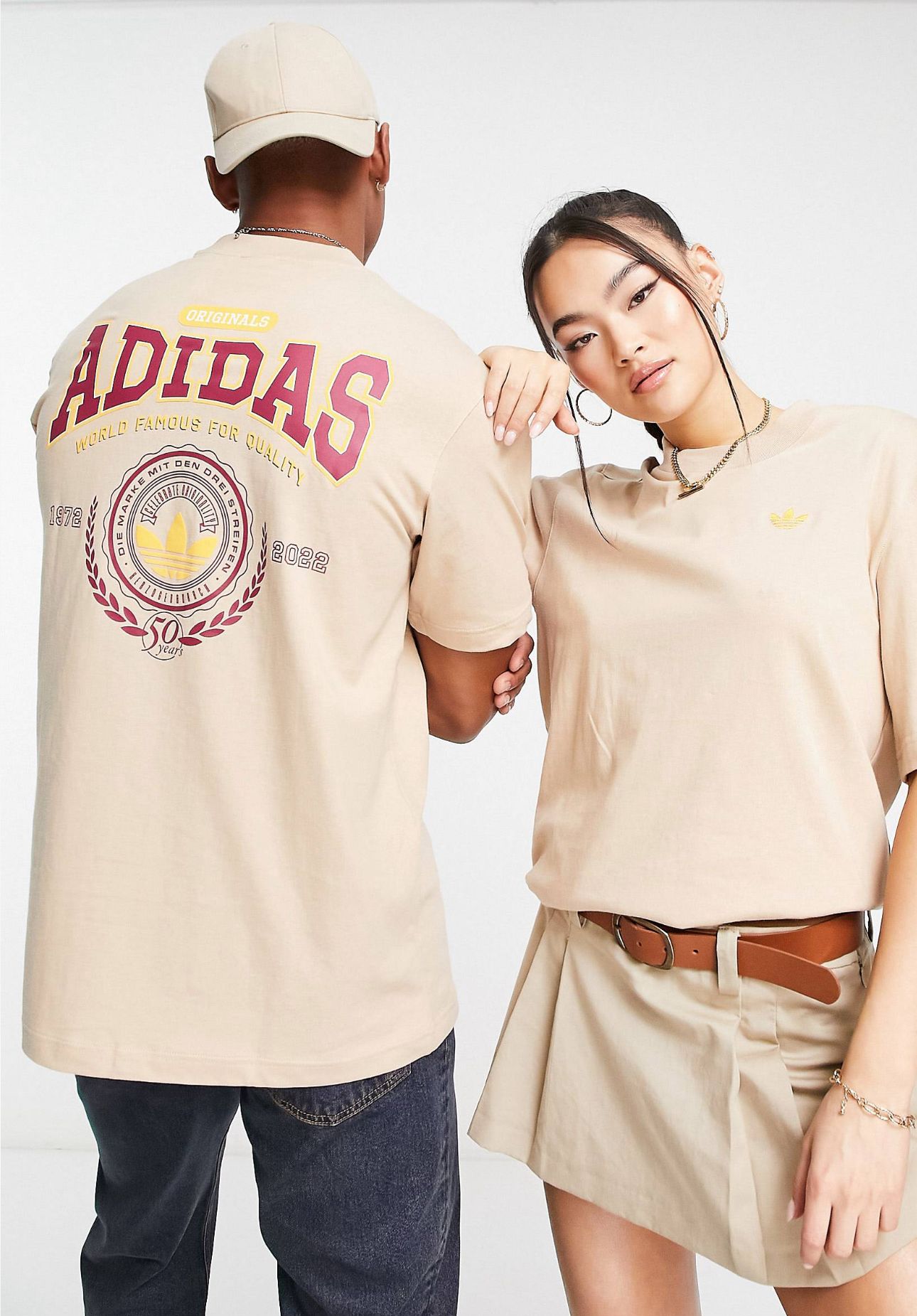 T-shirt Adidas original crema con letras ADIDAS en rojo vino y logotipo de la marca en amarillo.