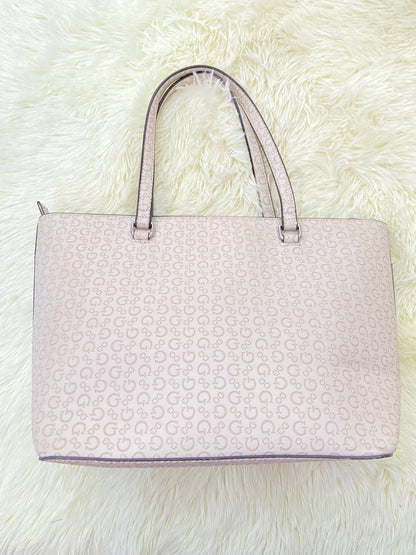 Cartera GUESS original, grande, rosado palo crema con letras G y placa GUESS en plateado en frente.