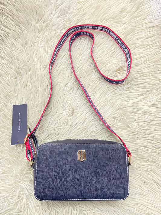 Cartera/Crossbody Tommy Hilfiger Original color azul marino con placa de la marca al frente en color dorado, correa en color azul marino rojo y blanco con nombre de la marca.