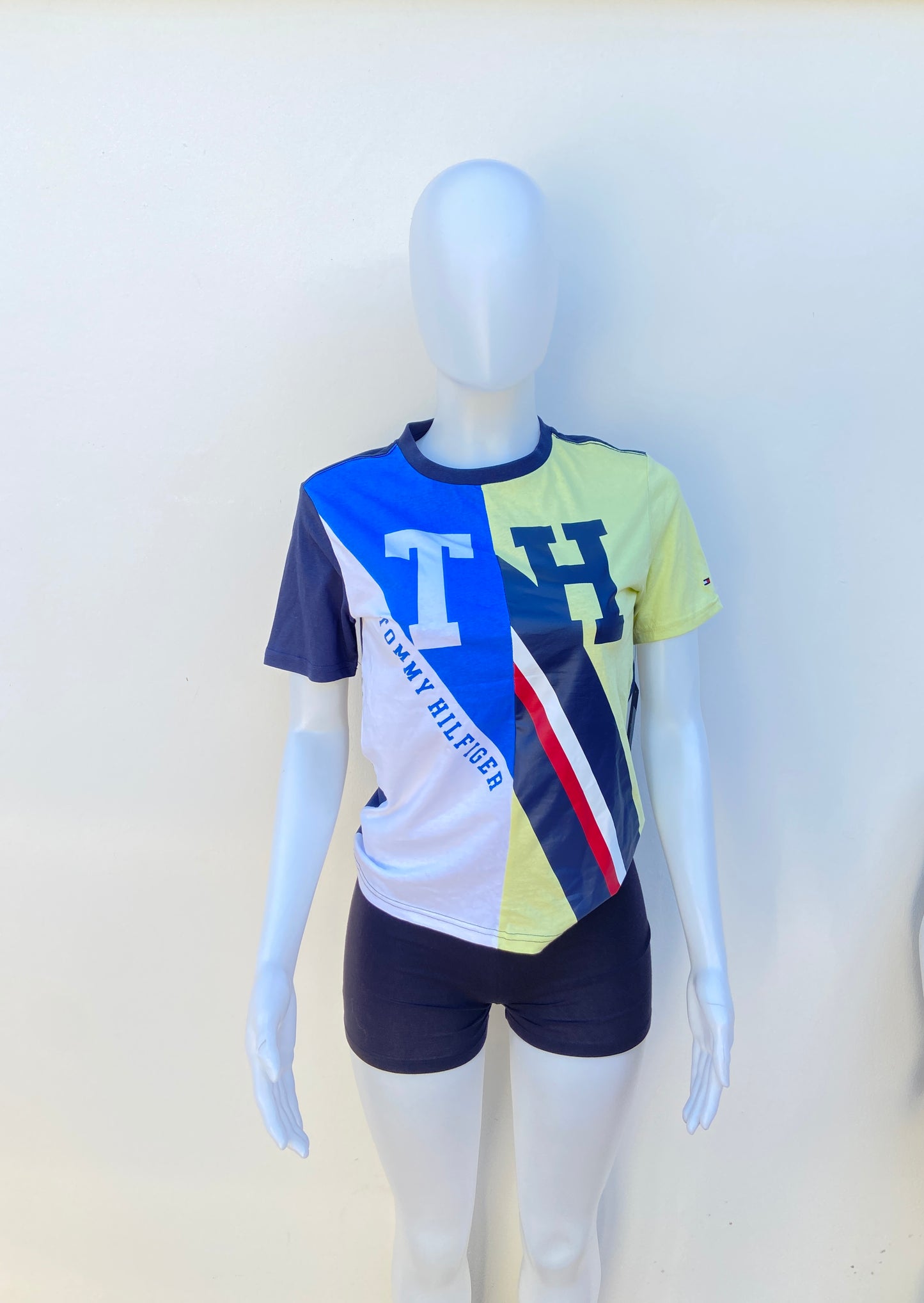 T-shirt Tommy Hilfiger original azul marino con amarillo claro y rayas en azul y blanco, T H en azul y blanco.