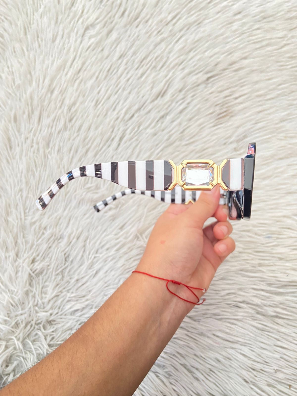 Lentes, negro con micas en color morado/ negro oscuro y montura con rayas blancas y negra y detalles en color dorado.