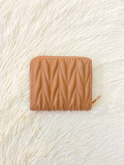 Monedero color marrón con diseño acolchado, cierre de zíper y espacio para tarjetas y más.