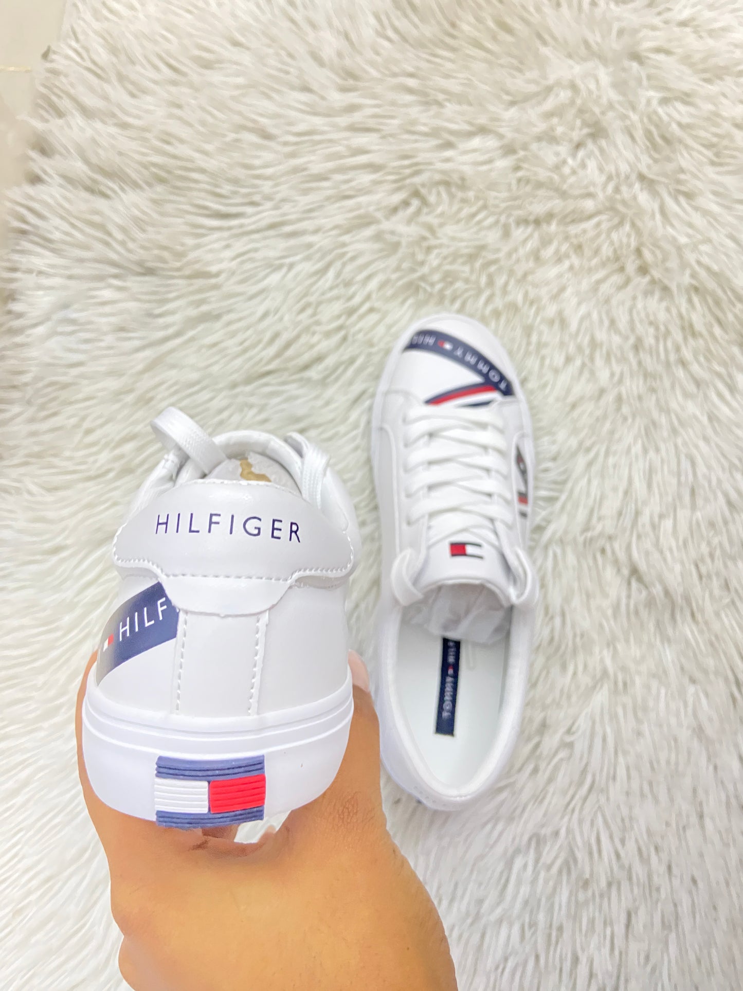 Tenis Tommy Hilfiger Original blanco con líneas en azul marino con letras Tommy Hilfiger en blanco y logotipo de la marca en la parte trasera.