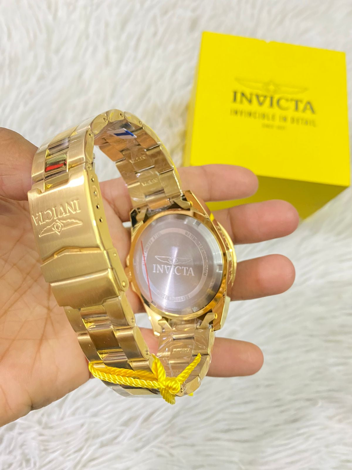 Reloj INVICTA original dorado con detalles en color blanco y letras INVICTA grabado en los lados.