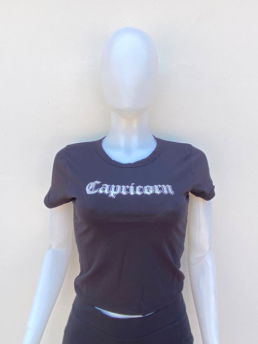 Top negro con letra al frente en color plateado y piedras plateadas alrededor Capricorn