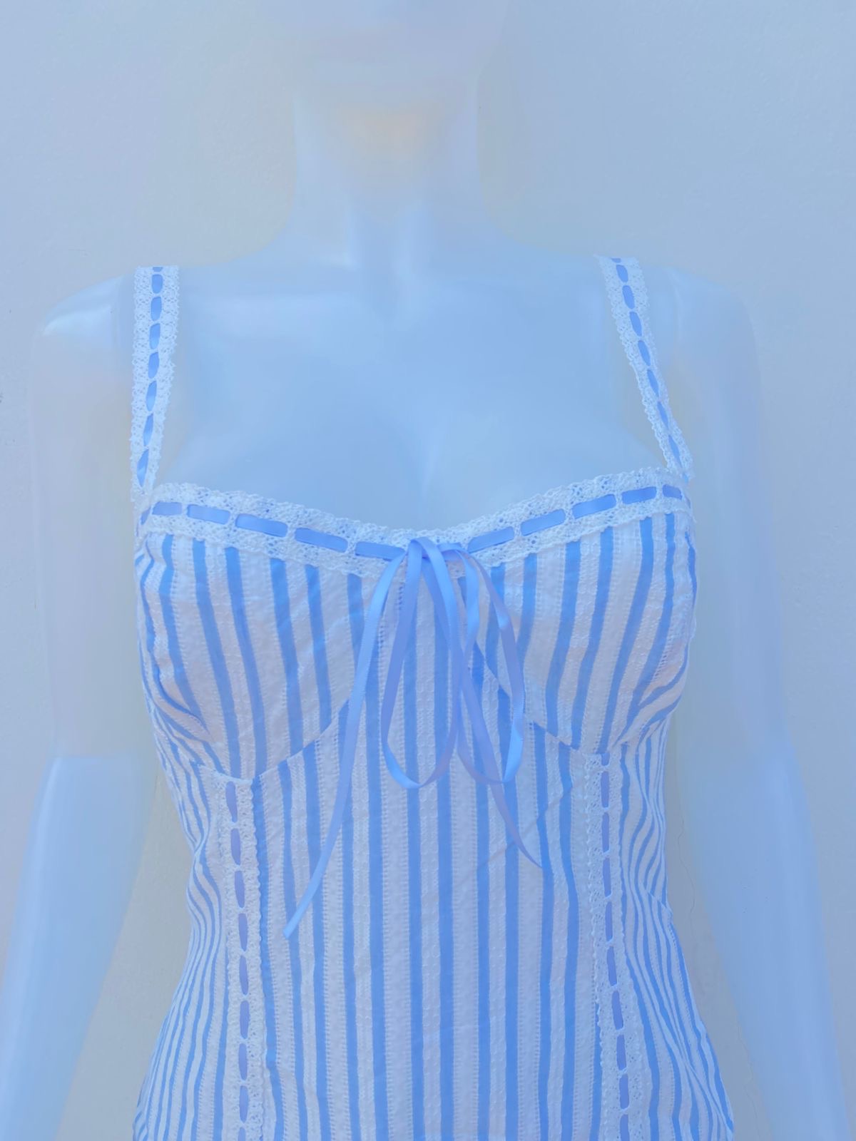 Vestido azul claro con rayas blancas con encaje y lazo en el medio en color azul
