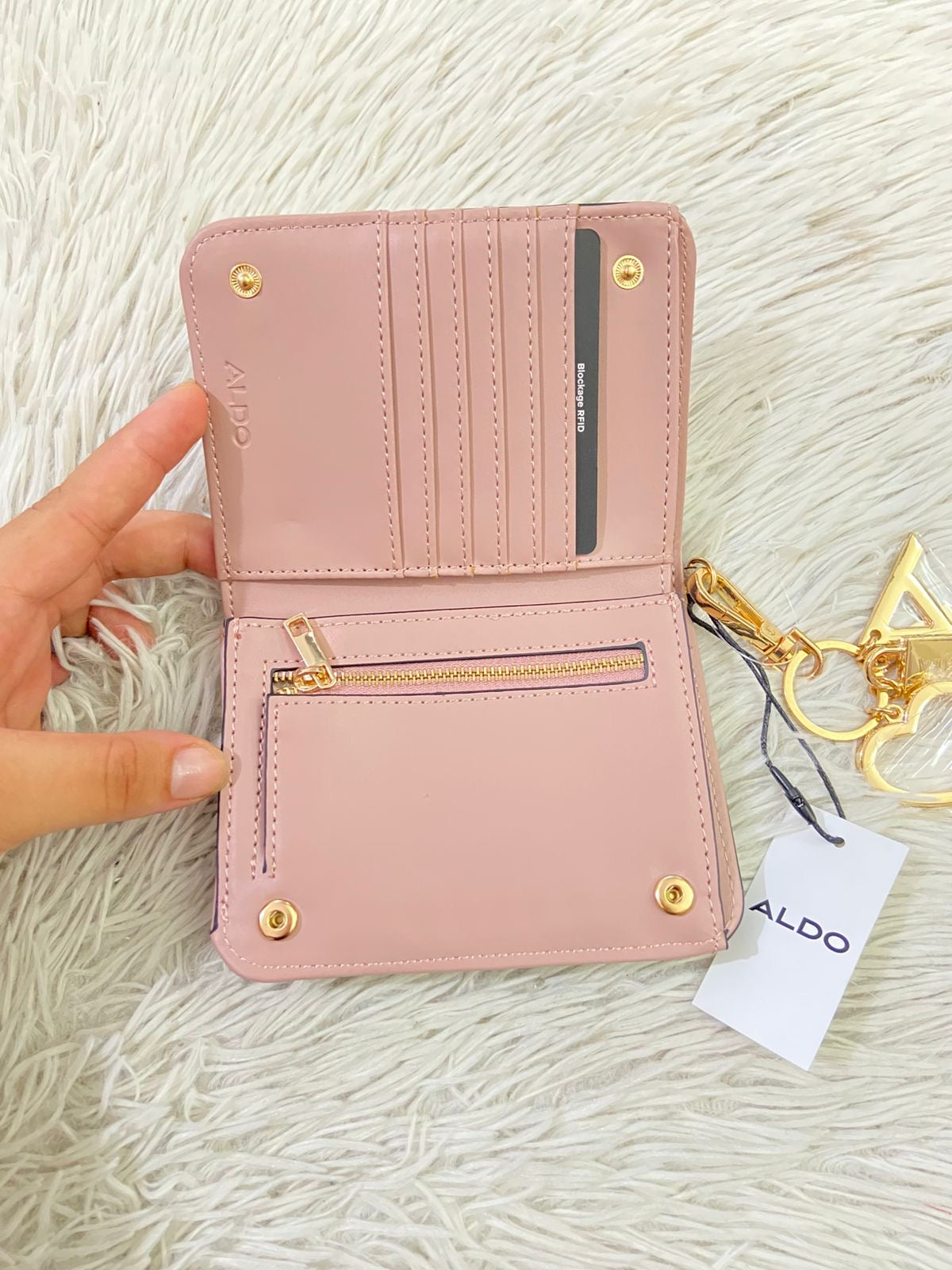Monedero/ Cartera ALDO Original en color crema con placa de la marca al frente en color dorado y llavero adicional.