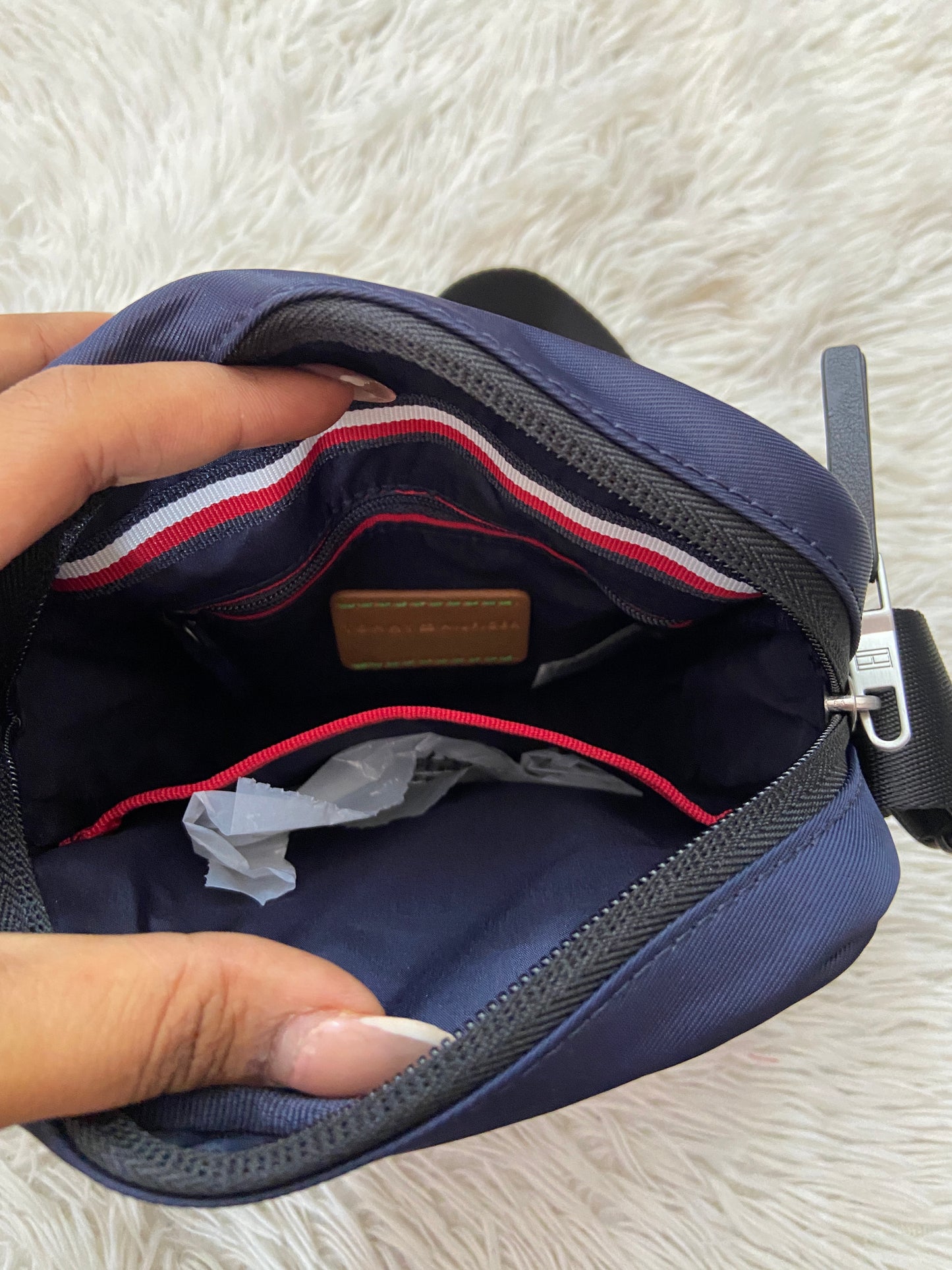 Bulto Tommy Hilfiger original azul marino, con negro y placa TOMMY HILFIGER en plateado.