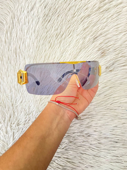 Lentes con protección UV 100-400 para proteger tu visión. En color negro con detalles dorados en los lados.