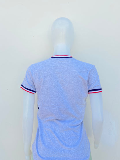 T-shirt U.S POLO ASSN. original en color gris con cuello V, logotipo de la marca al frente y banda en color azul marino, blanco y rojo en el cuello y mangas.