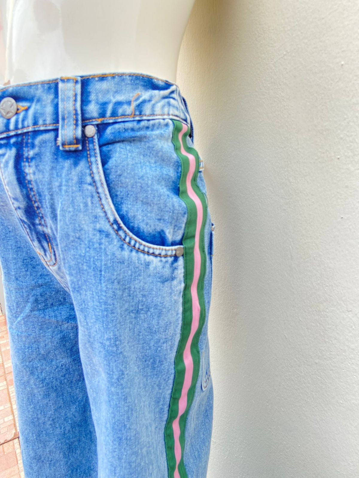 Pantalon jean en color azul claro con lineas de color verde y rosado en los lados, super ancho abajo.