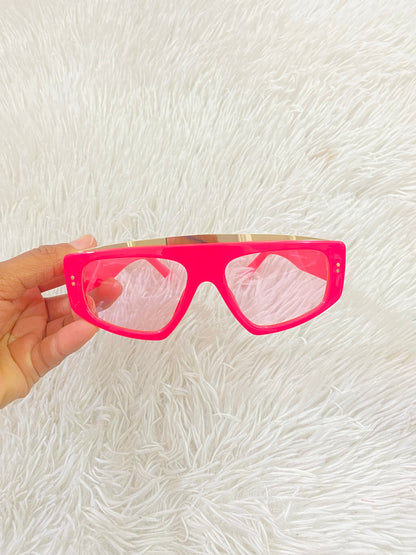 Lentes con protección UV 100-400 para proteger tu visión. Rosado fucsia con micas transparente y diseño dorado.