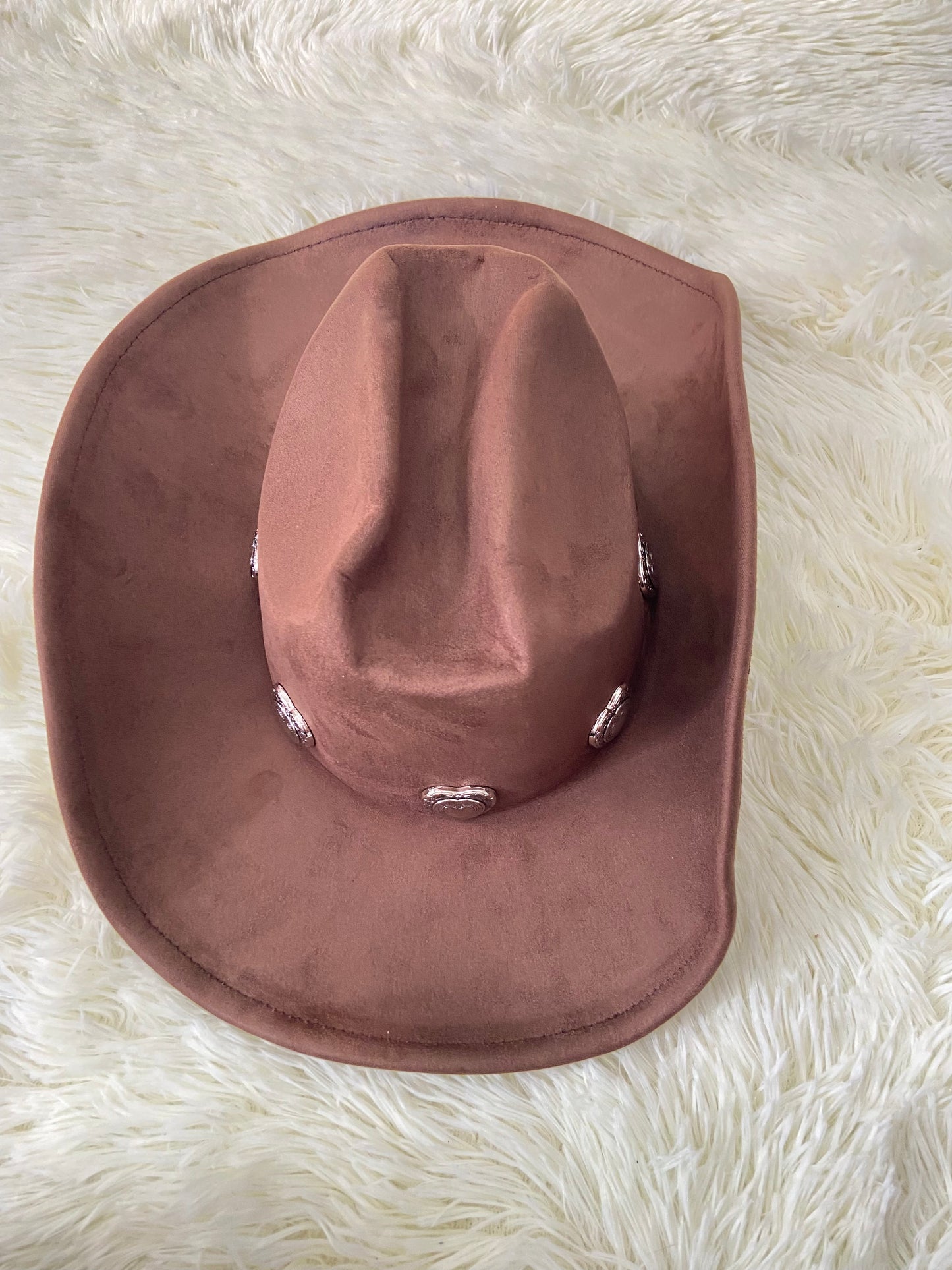 Sombrero, marron oscuro con placas de corazón al rededor en plateado, estilo vaquero.
