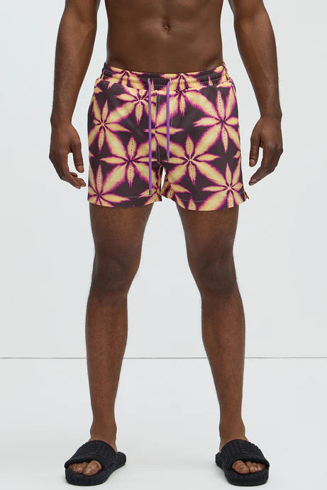 Bañador Baggy morado con estampado de una hoja amarilla.