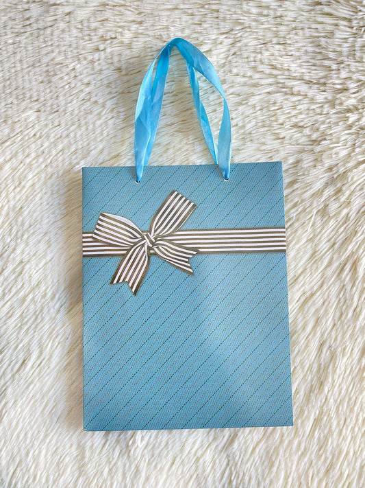Shopping azul con lazo de regalo en blanco y negro en rayitas y lazo en azul.